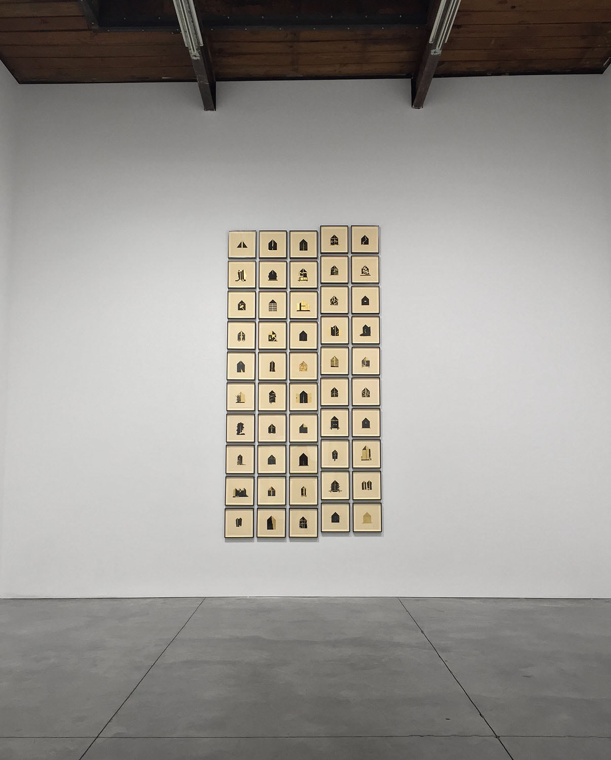 Installation view of Folding House at Gallery Espace, with fifty framed house collages rising in a tall grid
